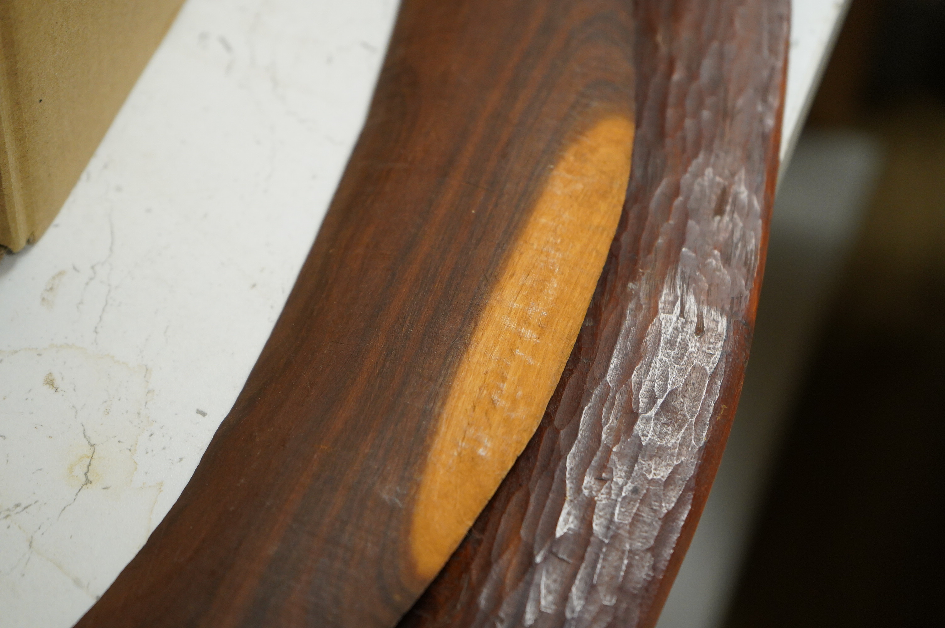 Five ethnographic items; an early 20th century chip carved Australian boomerang-60cm long , together with a later example, a Benin bonds of a warrior seated on a stool, a Makonde African carved figure group and an Africa